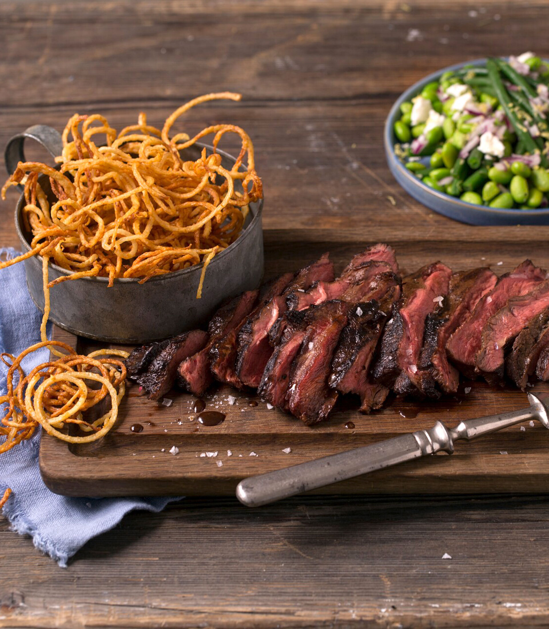 Grillet flat iron steak med curly fries og edamame-salat