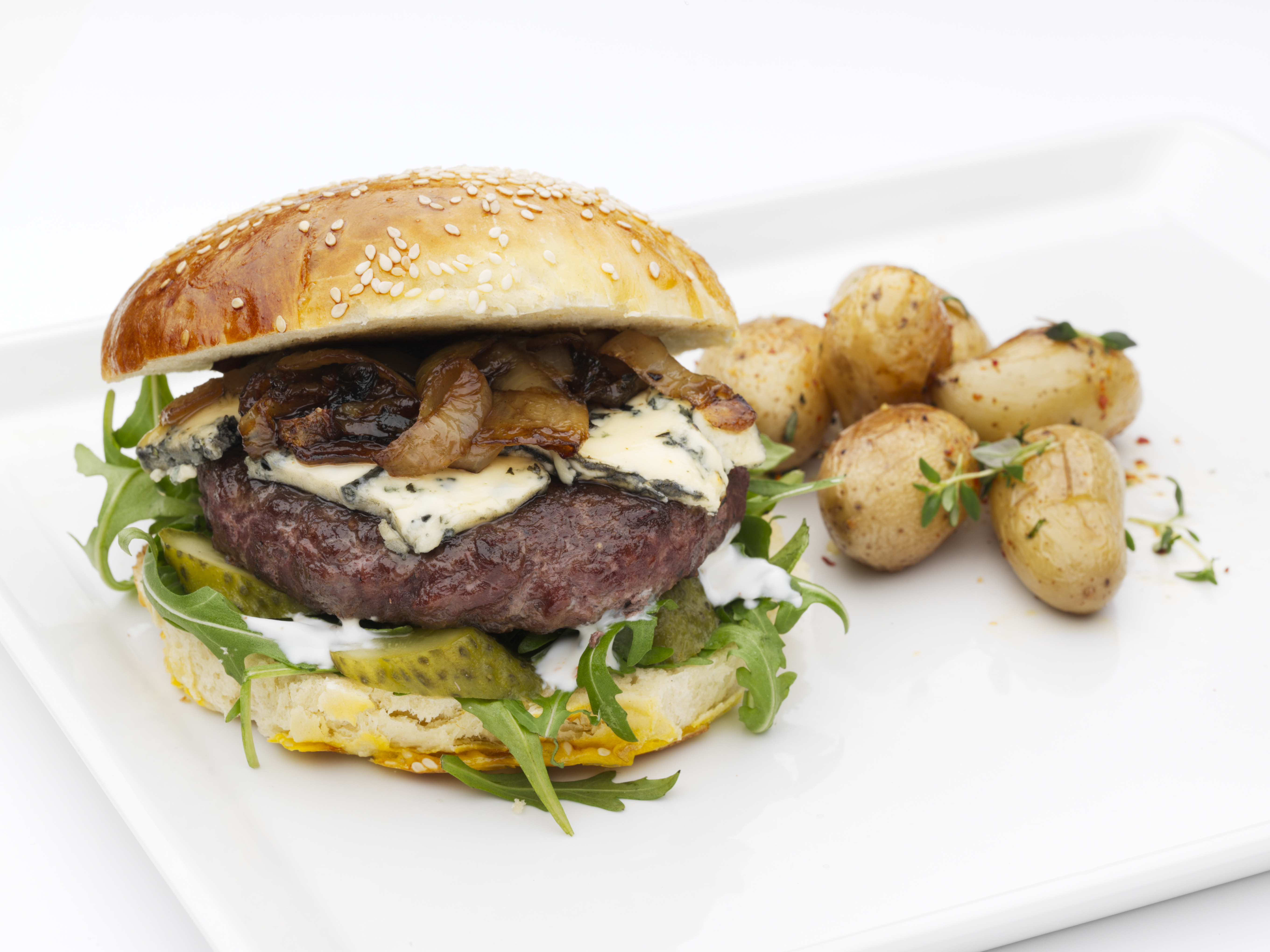 Hamburger med karamellisert løk og blåmuggost servert med urtestekte poteter