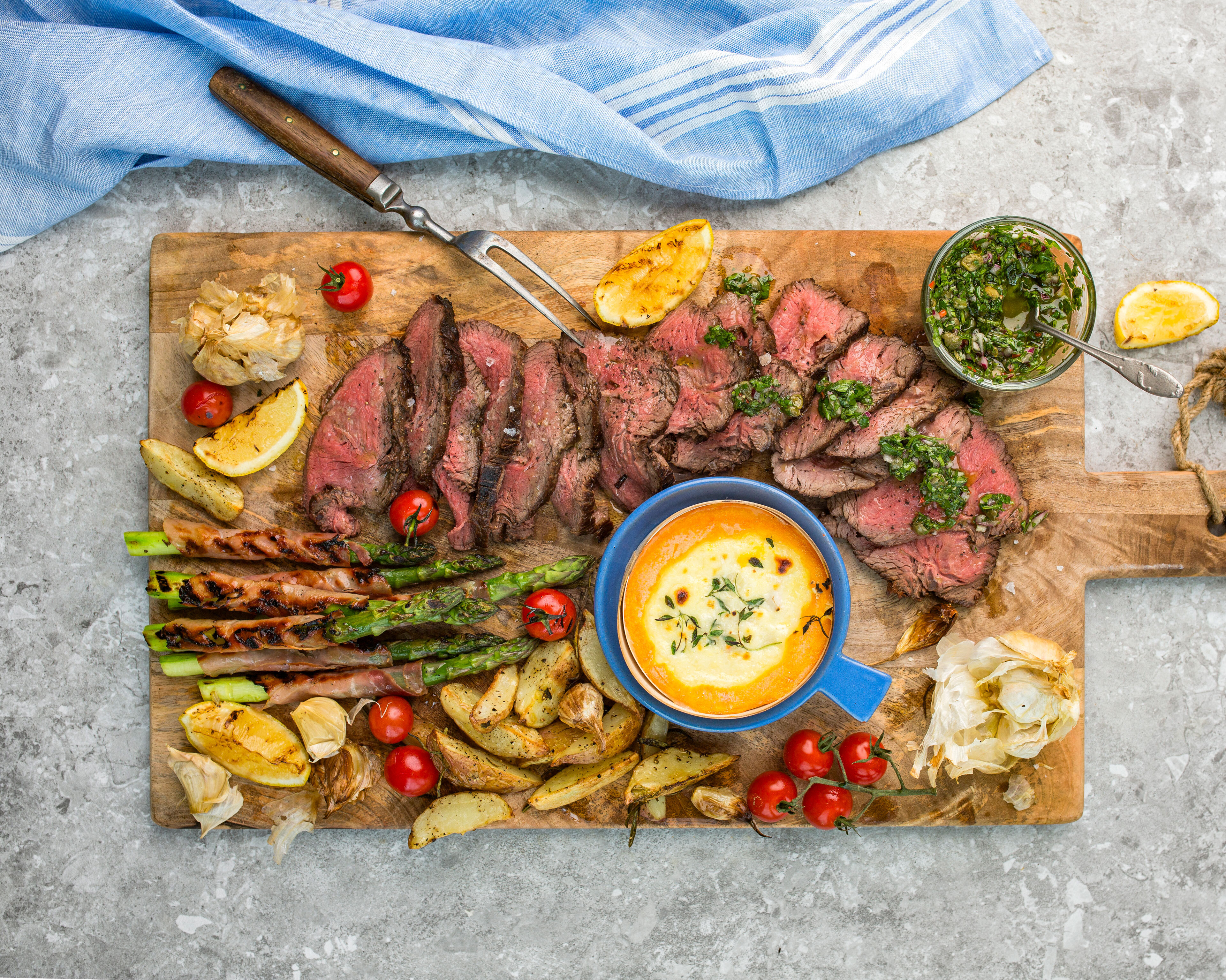 Planke med helgrillet storfe mørbrad med bakt Mont d´Or, båtpoteter, bakte hvitløk, skinkesurret asparges og chimichurri